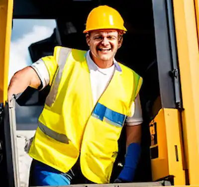 A compactor driver standing at his cabin door.