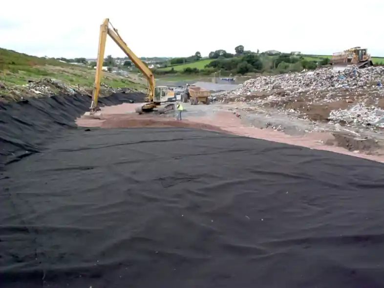 A completed landfill geomembrane liner with a long-reach excavator in use placing gravel on top of the lining to protect it from damage and ensure the environment is protected from leachate leakage.